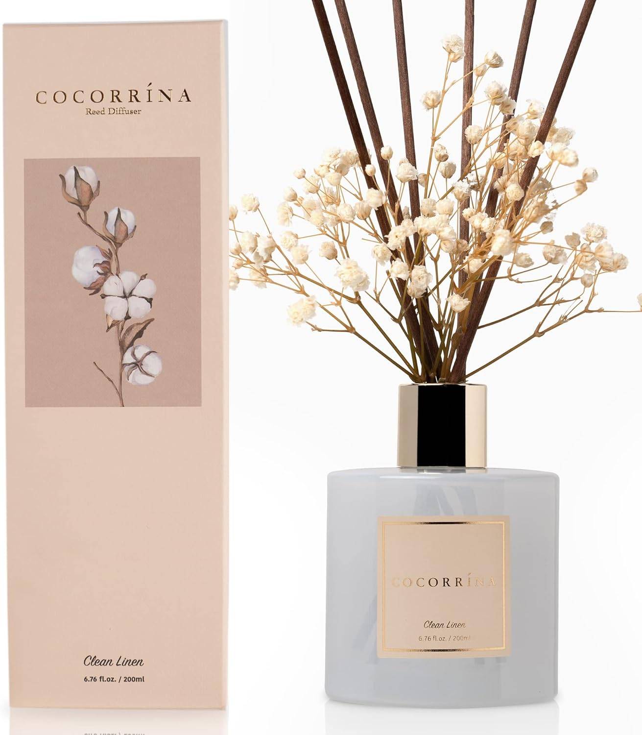 Frosted glass bathroom reed diffuser with dark reeds and dried white florals styled on a bright shelf with neutral decor and soft natural light.
