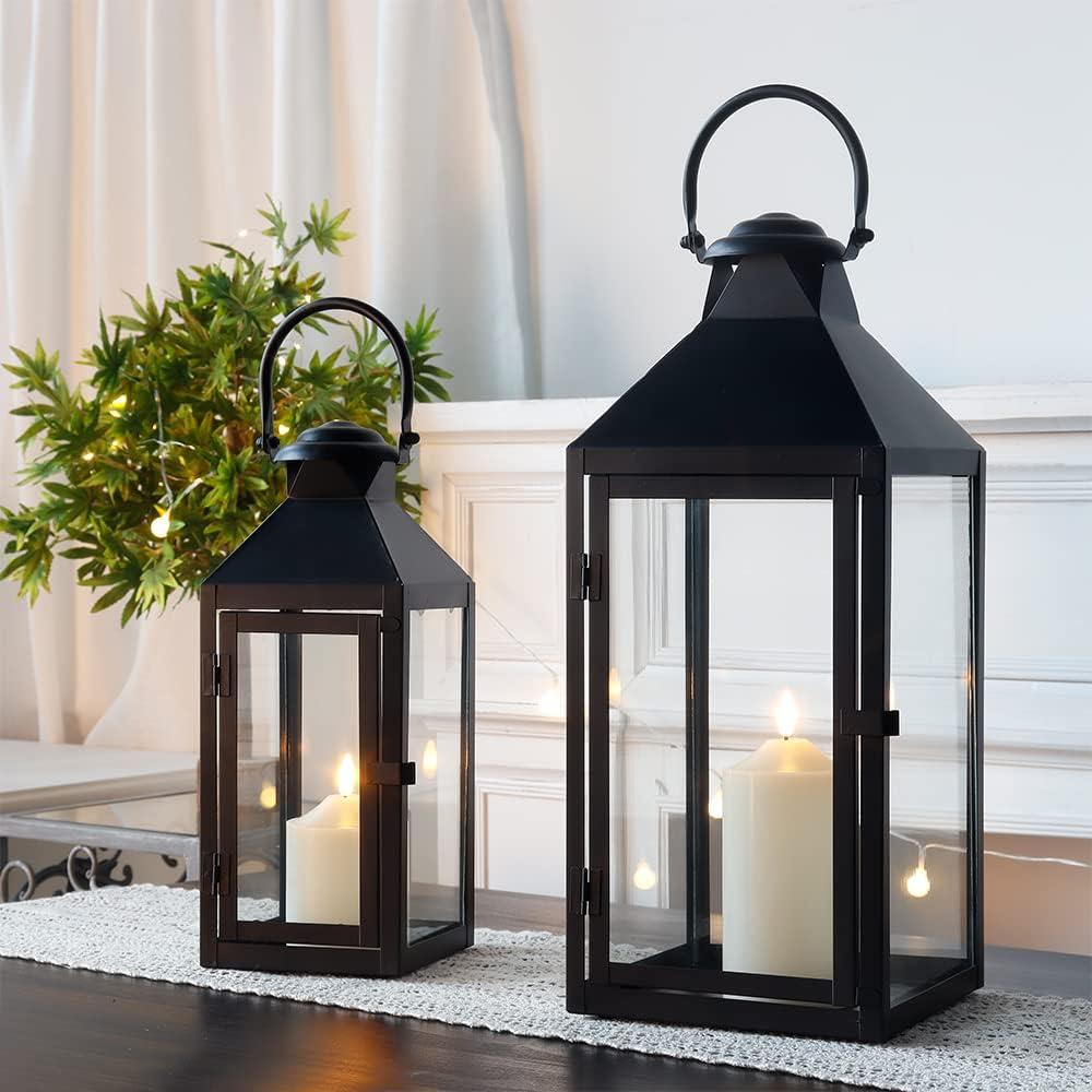 Two black metal candle lanterns with warm pillar candles on a lace runner, styled beside greenery and soft string lights for cozy neutral home decor