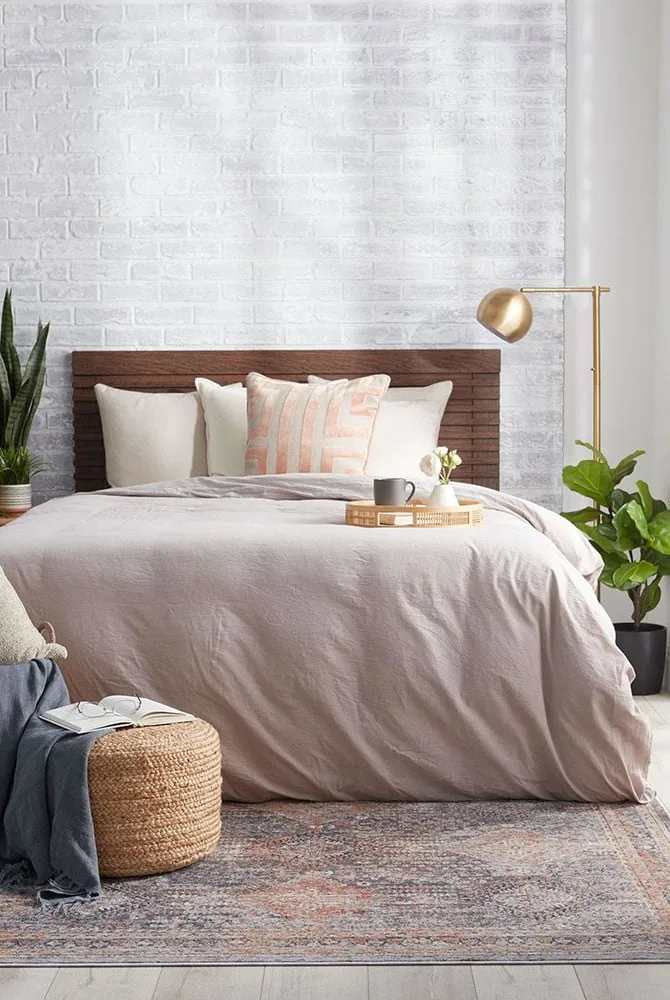 Sumptuously layered winter bed with washed flax linen sheets, lofty down duvet, waffle-knit coverlet, and folded wool throw blanket in warm oatmeal and charcoal